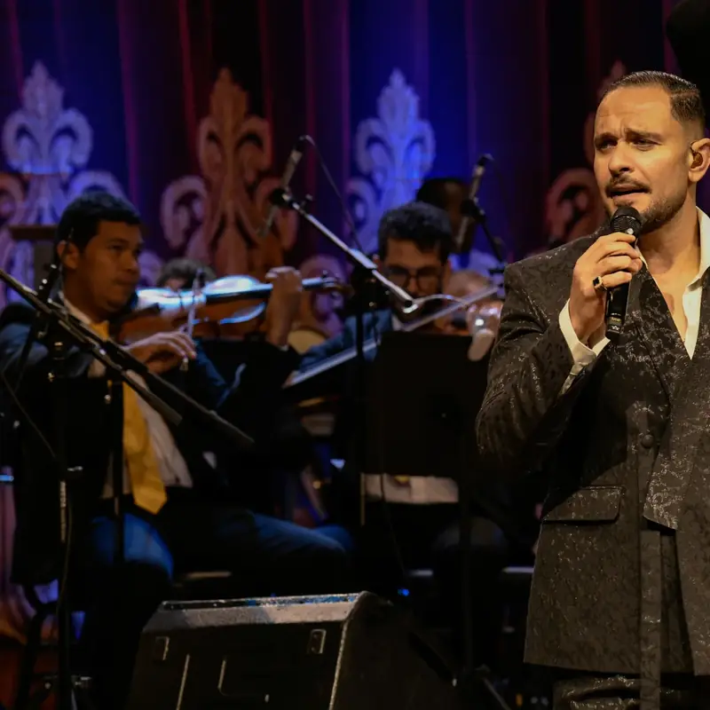 Cantor com microfone acompanhado pela orquestra